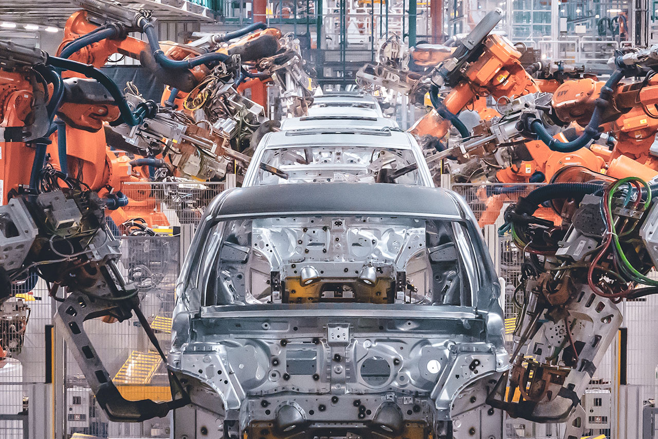 Aufnahme aus dem Karosseriebau bei der BMW Group mit Roboterarmen, die an den Karosserien arbeiten.