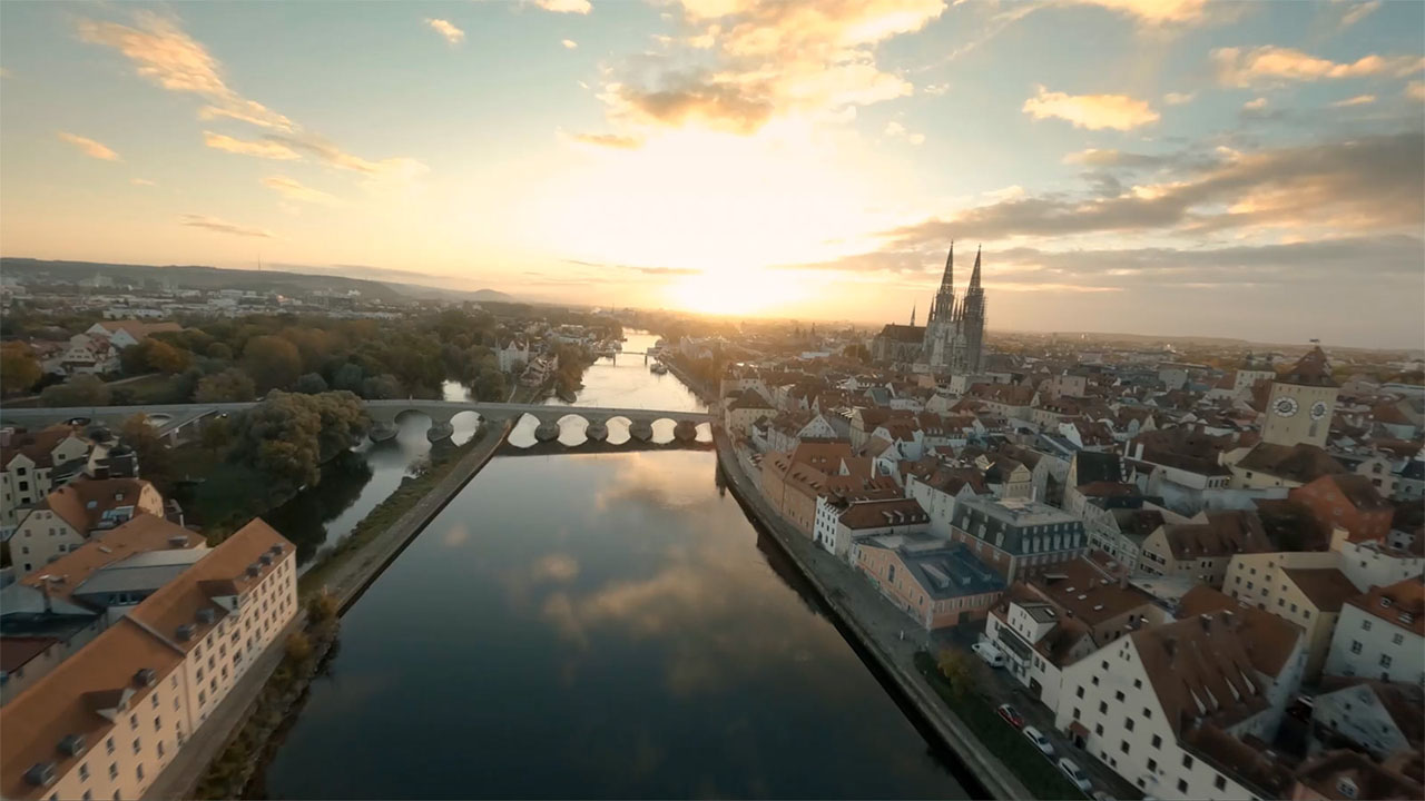 Panoramic view over the city of Regensburg with a large river and church tower at sunset