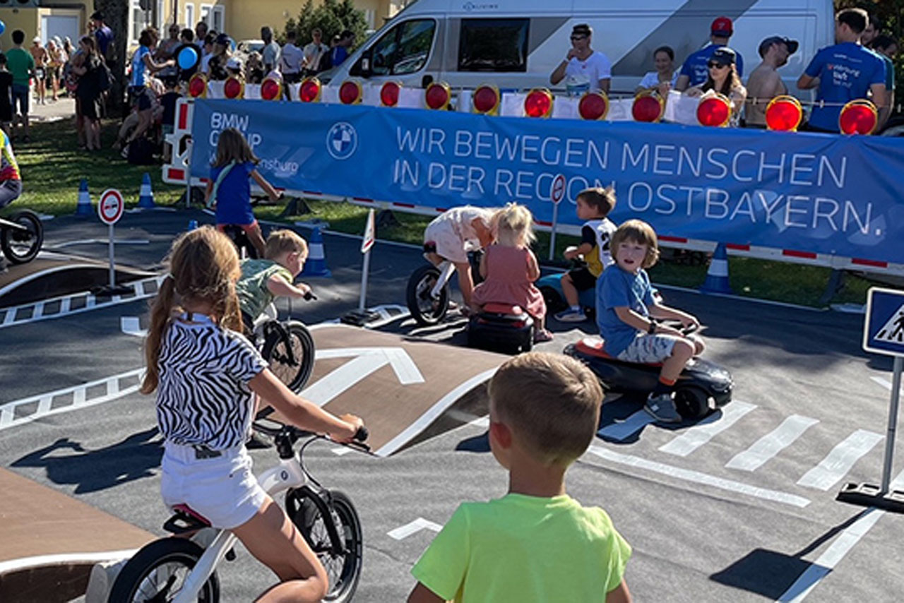 Young children ride through a course on balance bikes and other vehicles.