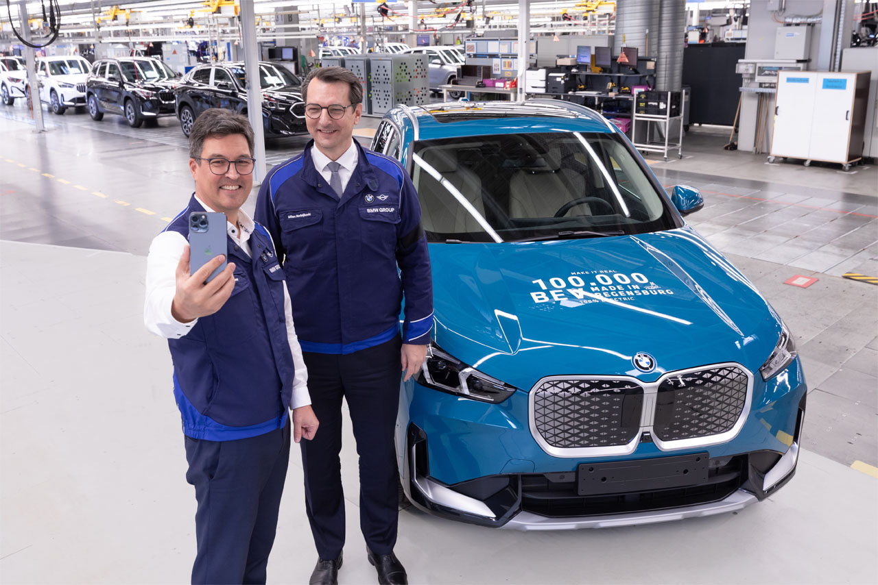 Zwei Männer stehen neben einem blauen BMW-Fahrzeug.