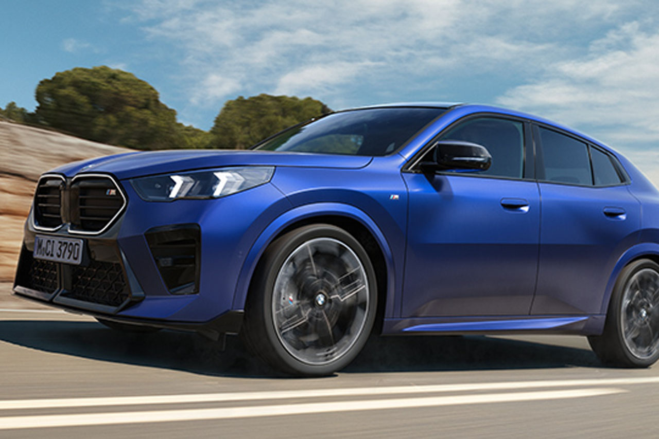 Blue BMW X2 driving on a country road.