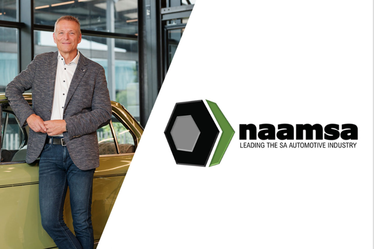 Man in gray blazer and white shirt leaning against a gold car next to the naamsa logo with the text 'LEADING THE SA AUTOMOTIVE INDUSTRY'