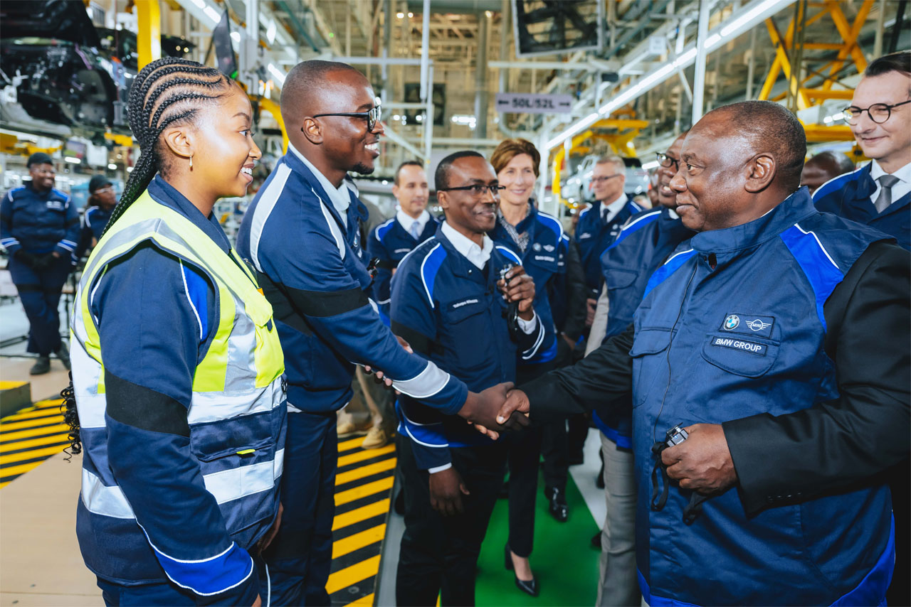 A team dressed in blue BMW jackets shaking hands.