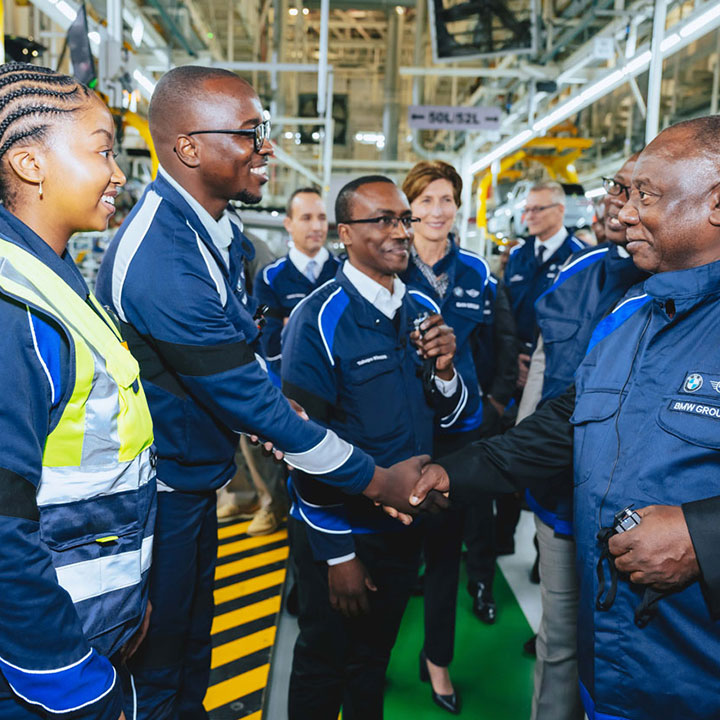 A team dressed in blue BMW jackets shaking hands.
