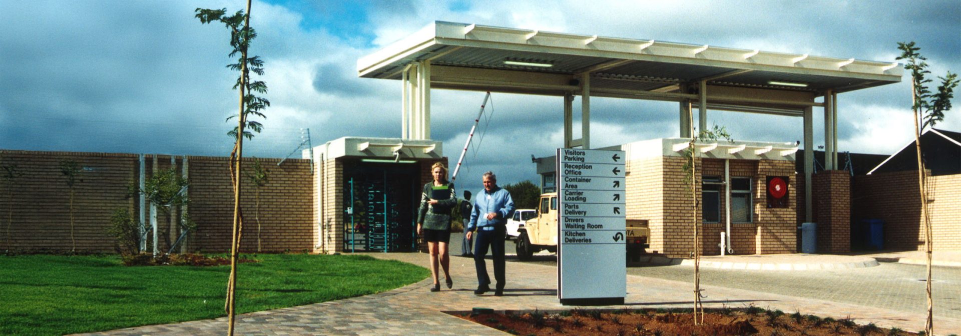  A man and woman stand together in front of a modern building, smiling and dressed casually.