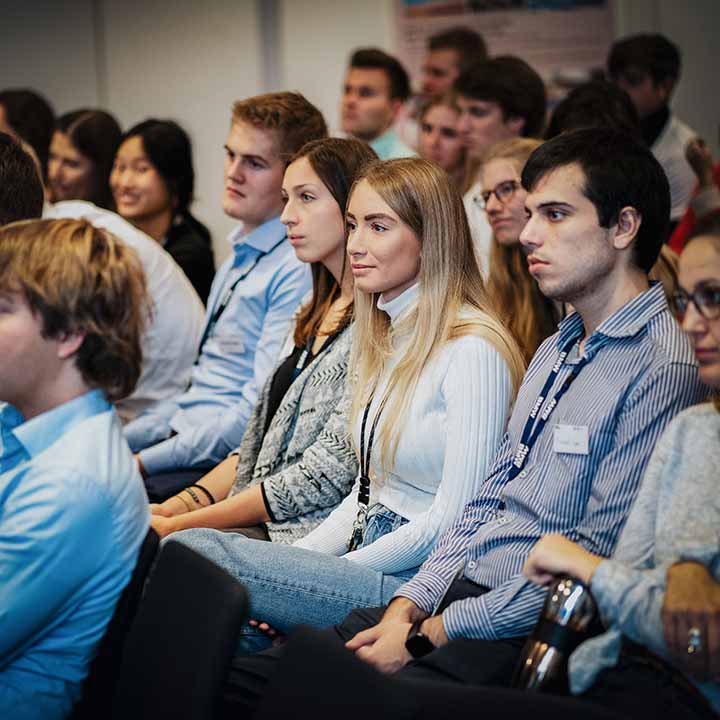 A group of recent graduates sitting together listening to a presentation.
