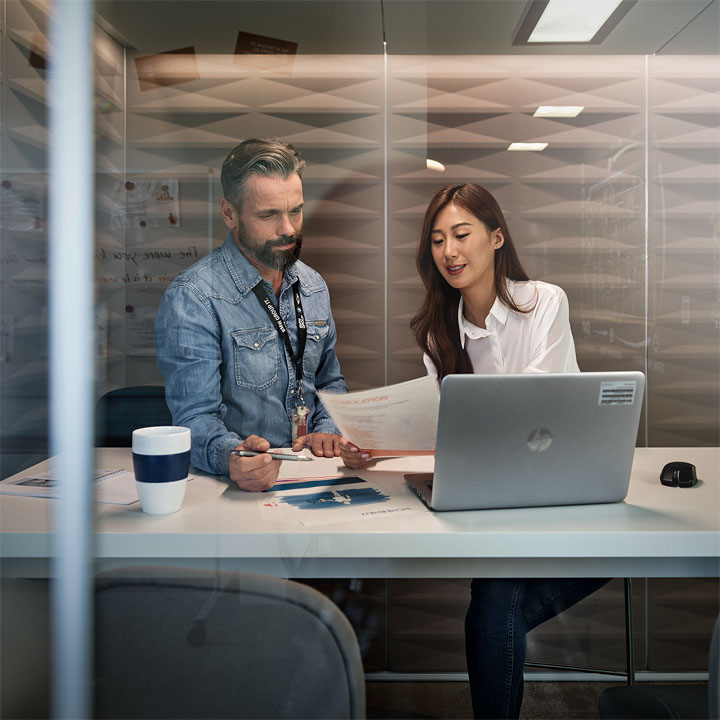 Two Students having a conversation in a glass-conference room at the BMW Group.