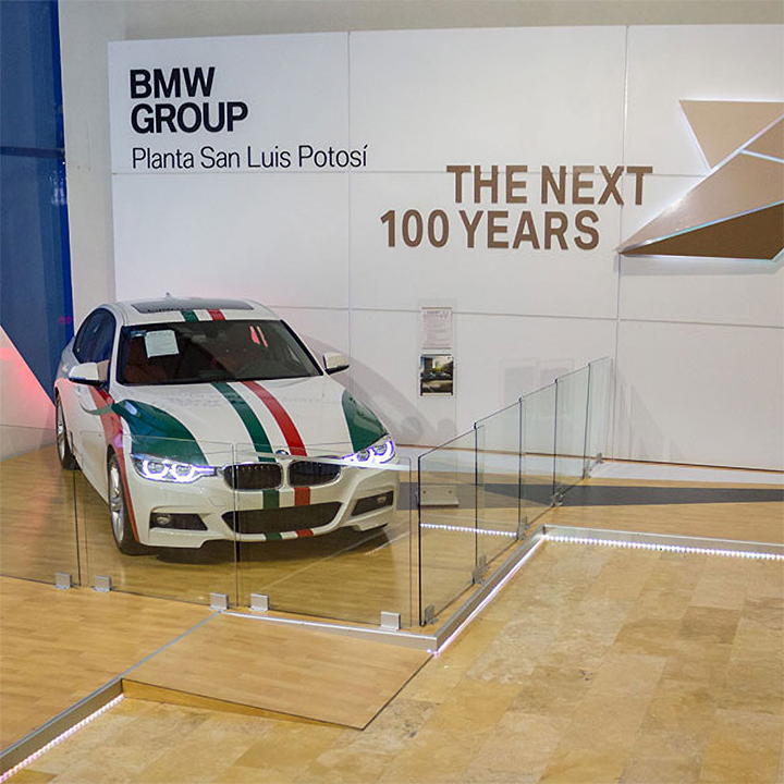 A BMW 3 series standing infront of a wall with "the next 100 years" written on it