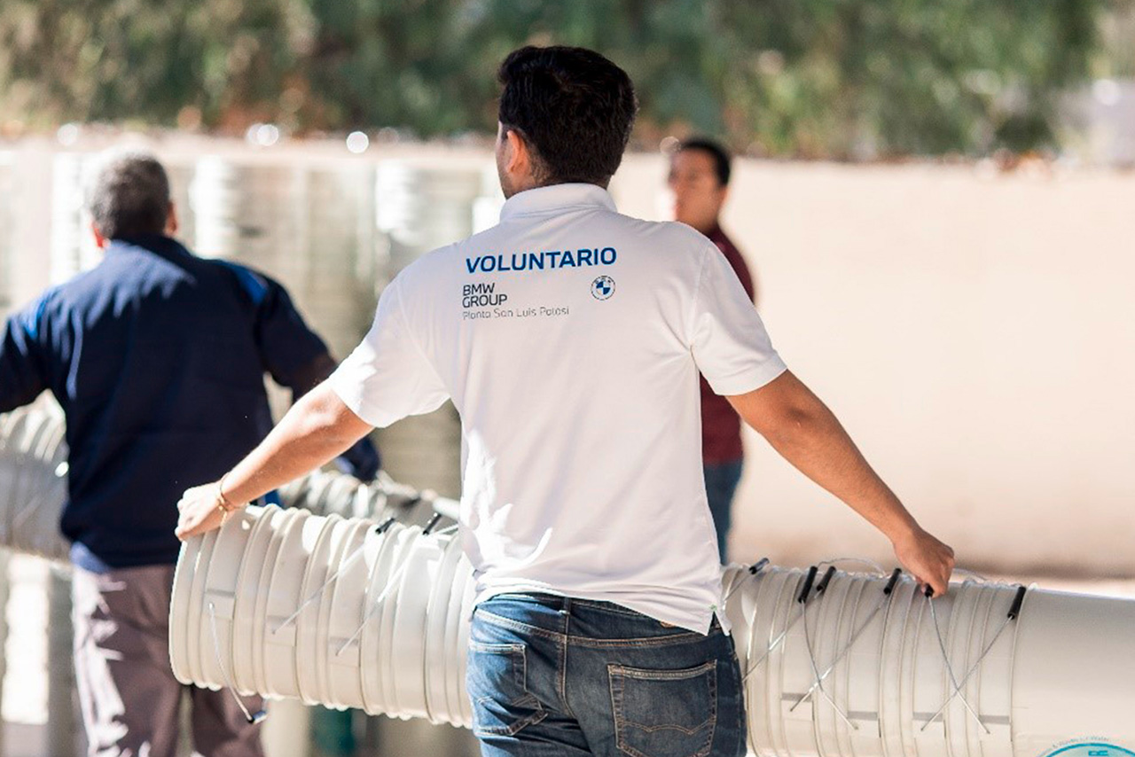 BMW Group volunteer at work holding a tower of buckets.