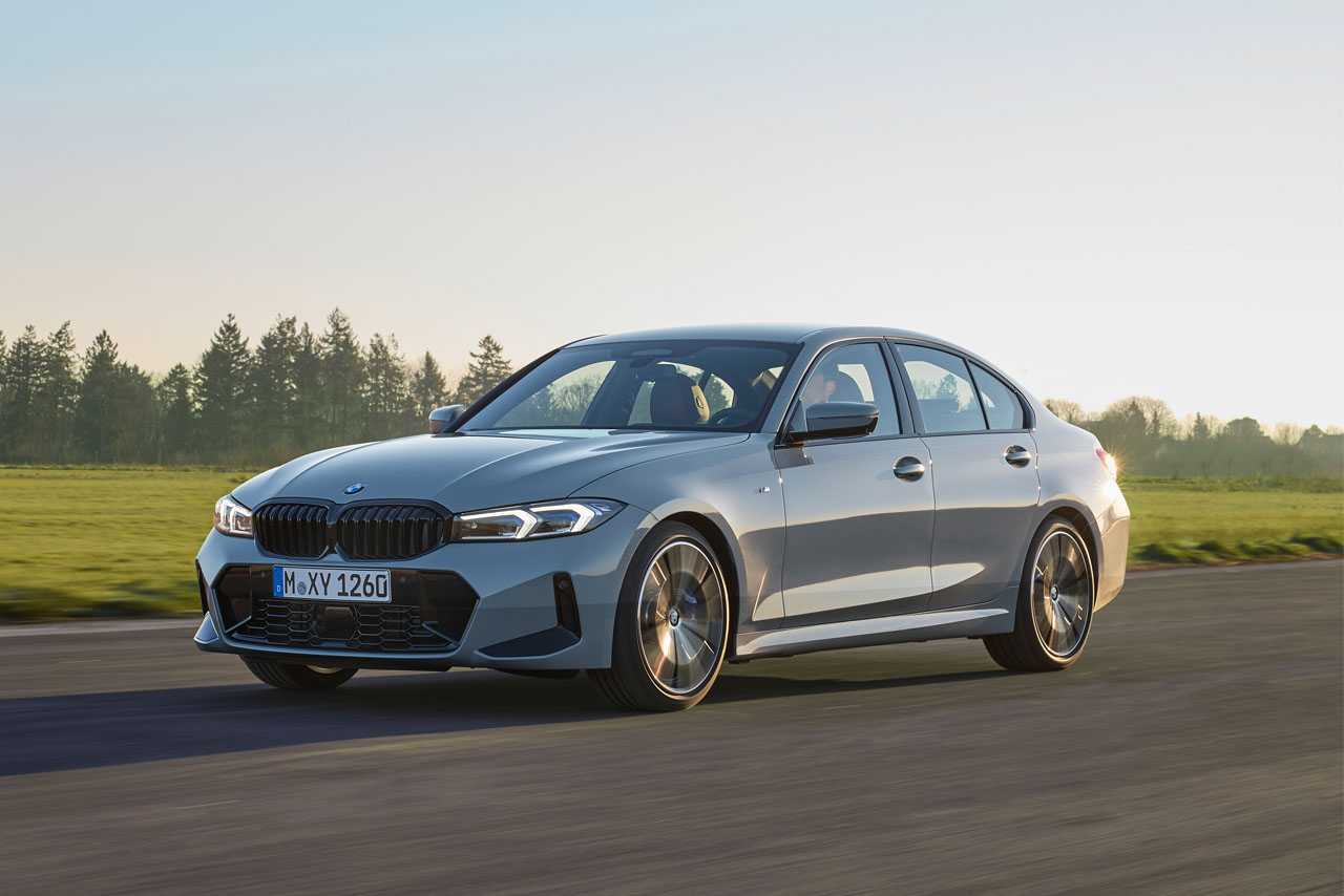 A grey BMW 3 series driving on a road through the nature.