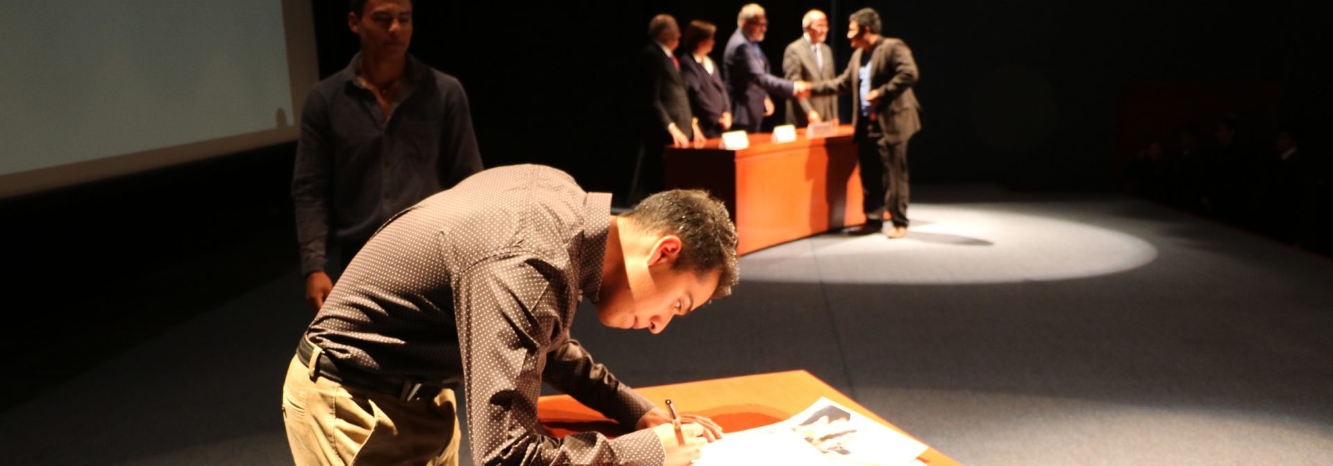 A man is standing at a table, signing something