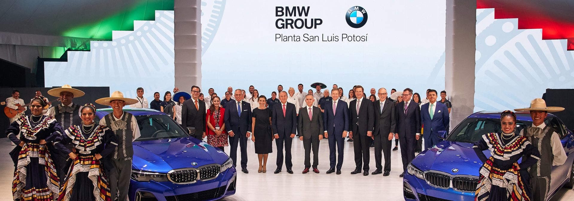 The BMW San Luis Potosi team posing with two dark blue BMW 3 series on a stage