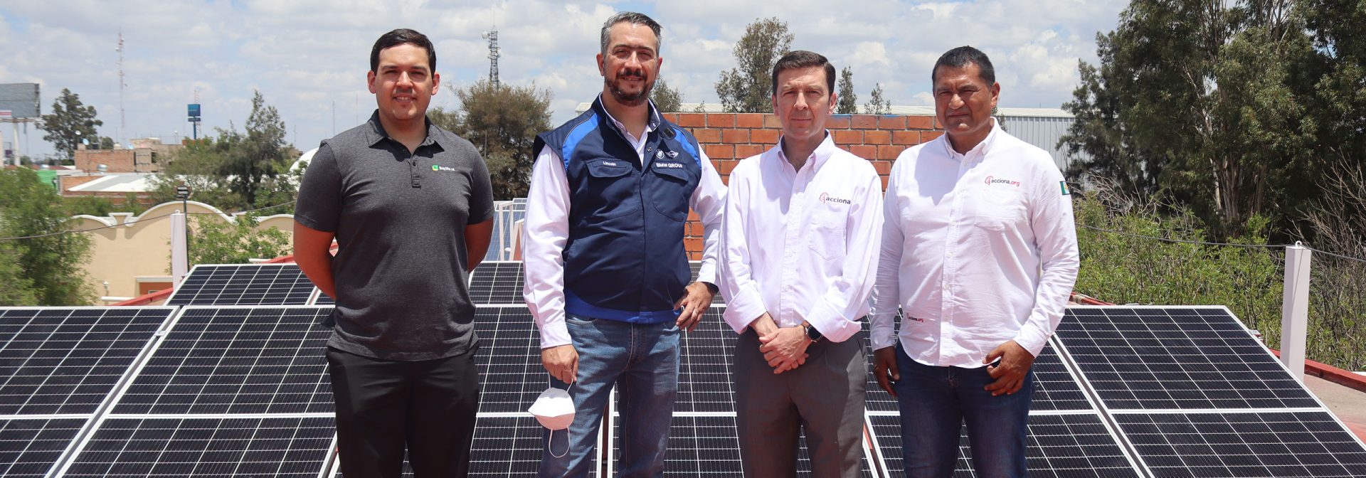 Four BMW employees taking a picture infront of some solar panels
