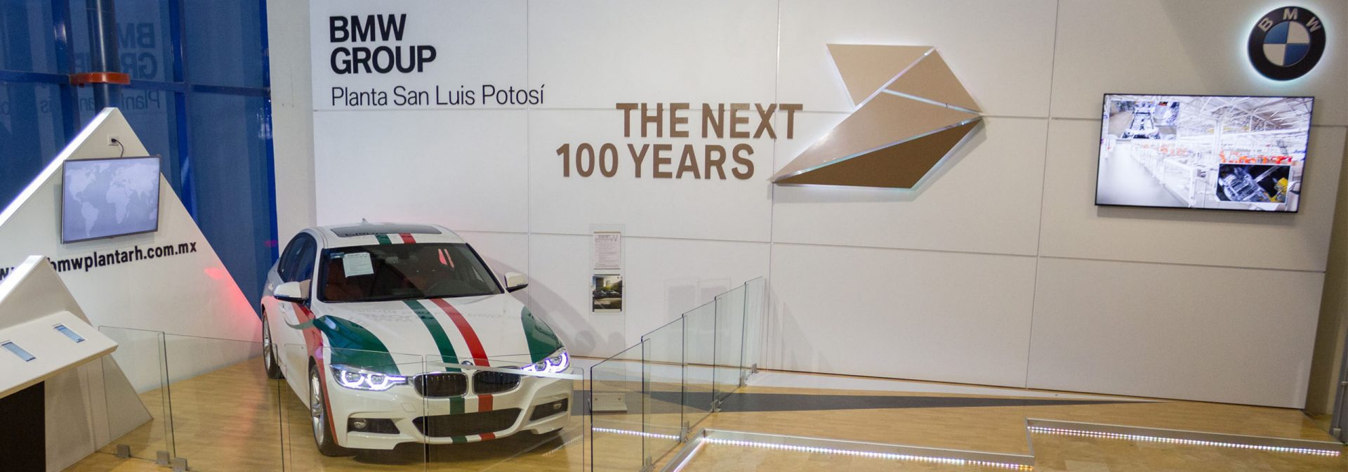 Un BMW serie 3 frente a un muro con la leyenda "os próximos 100 años".