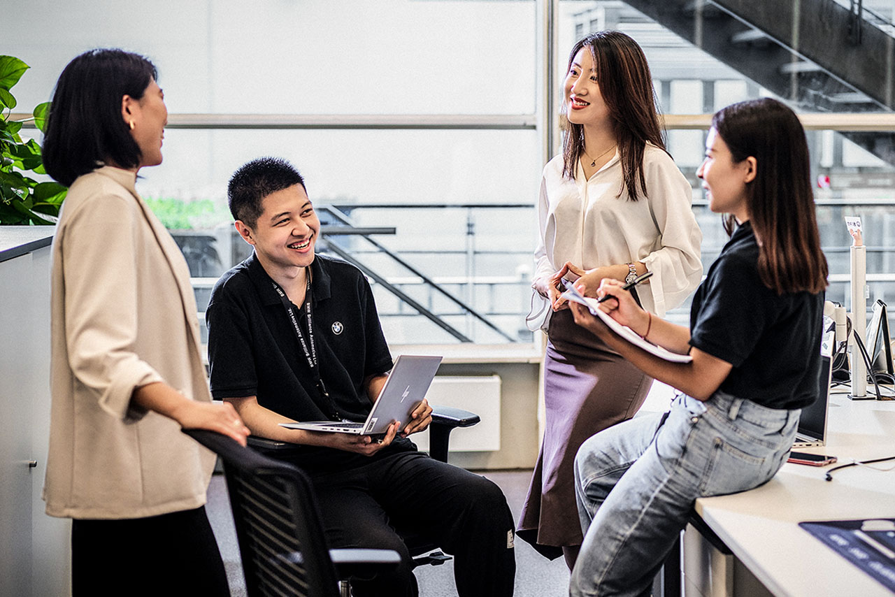 A group of three women and one man from Asia sitting around a table, enjoying each other's company.