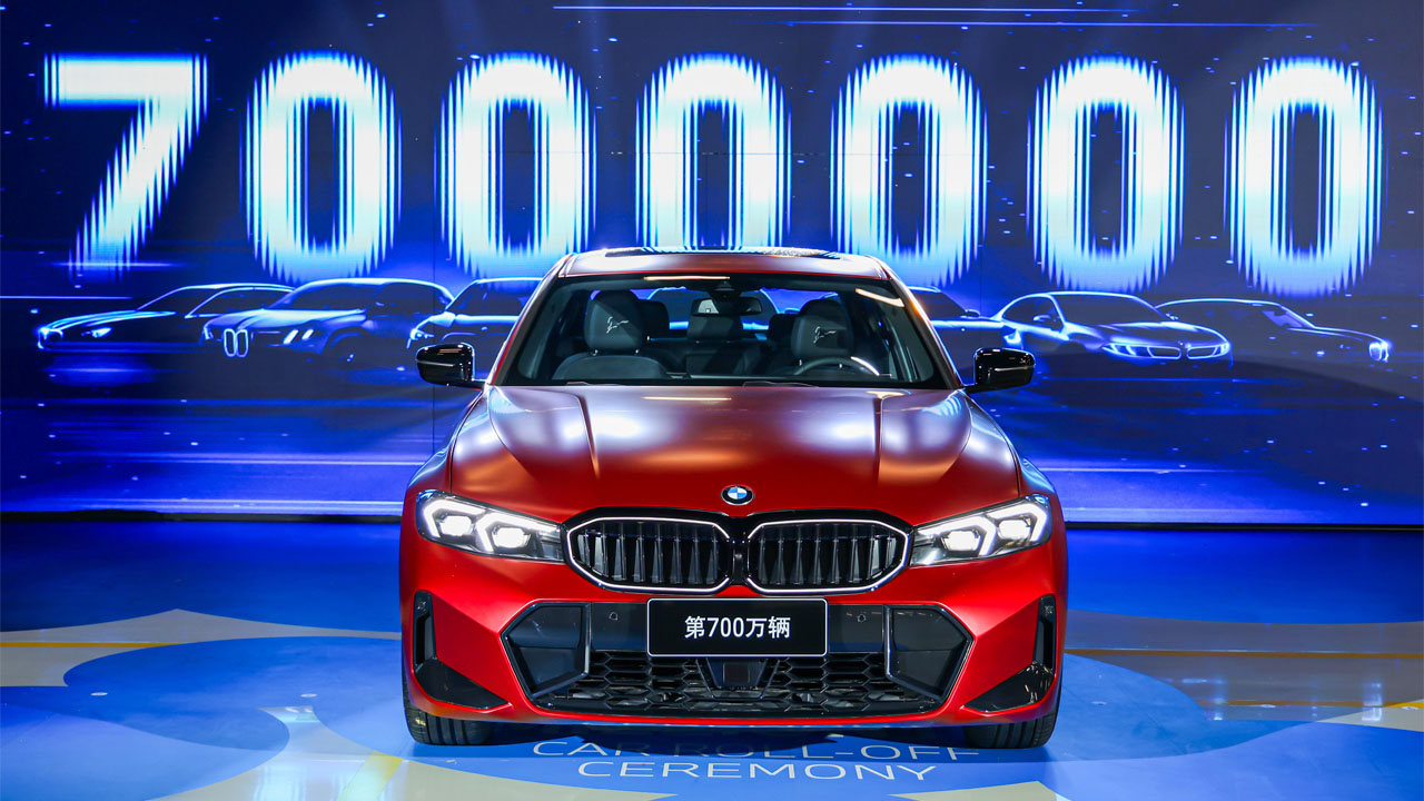 Red BMW car in front of a large digital display showing the number '7,000,000' with several cars in the background.