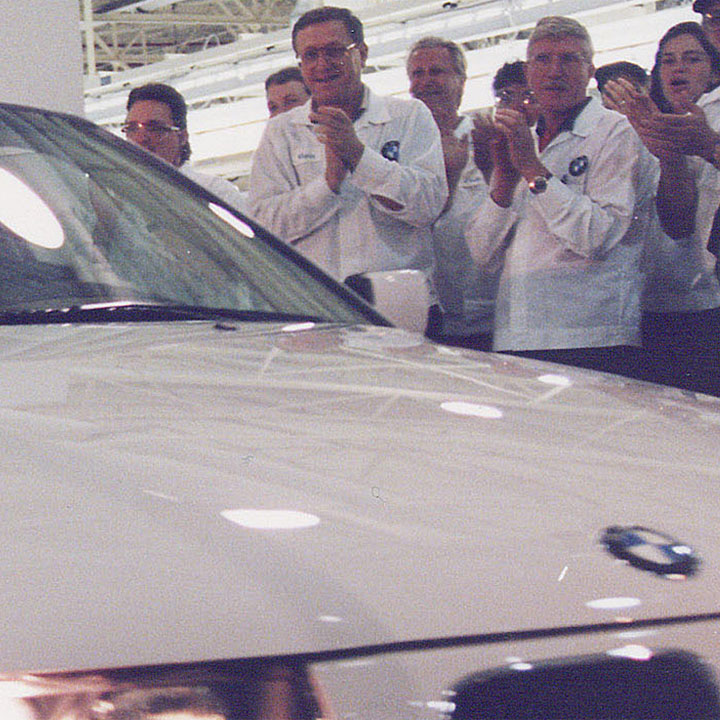 First BMW rolls off the line in spartanburg as associates gather around and celebrate by clapping. 