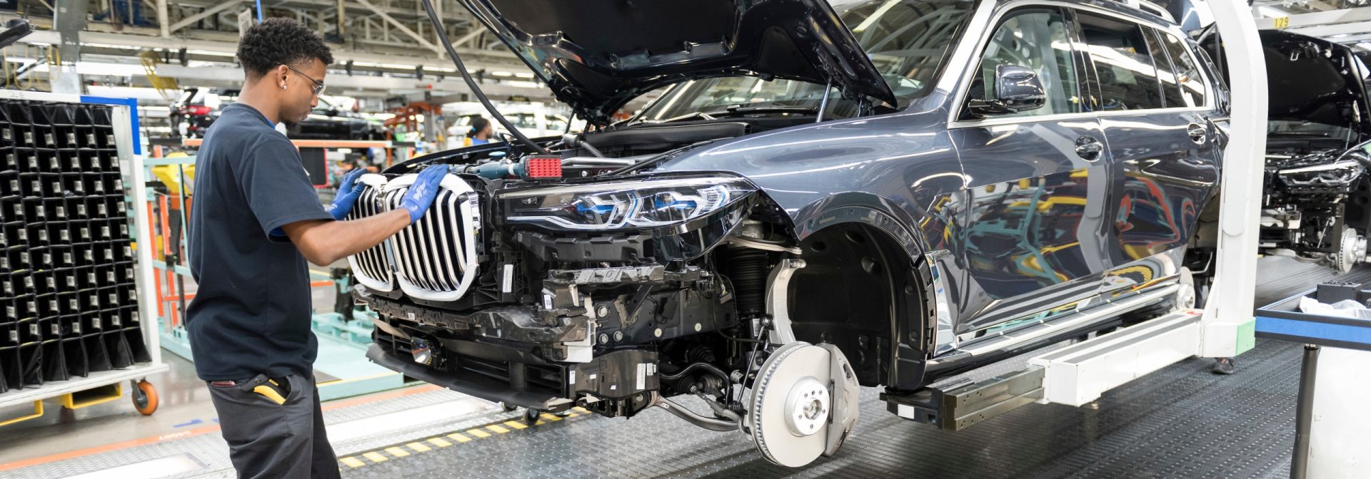The first BMW X7 Sports Activity Vehicle on the assembly with an associate putting on the grille.