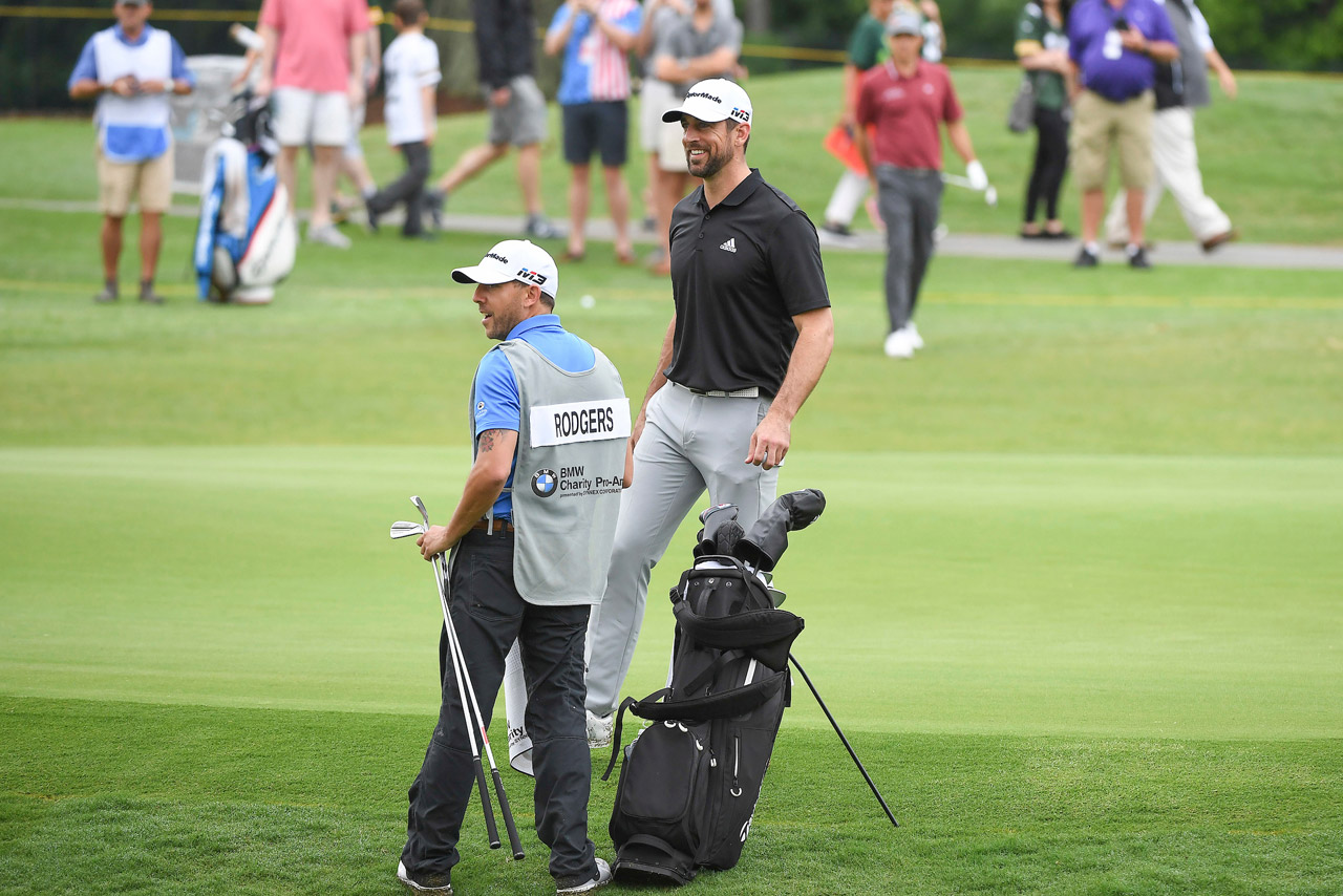 Aaron Rodgers and his caddy walking off the green smiling. 