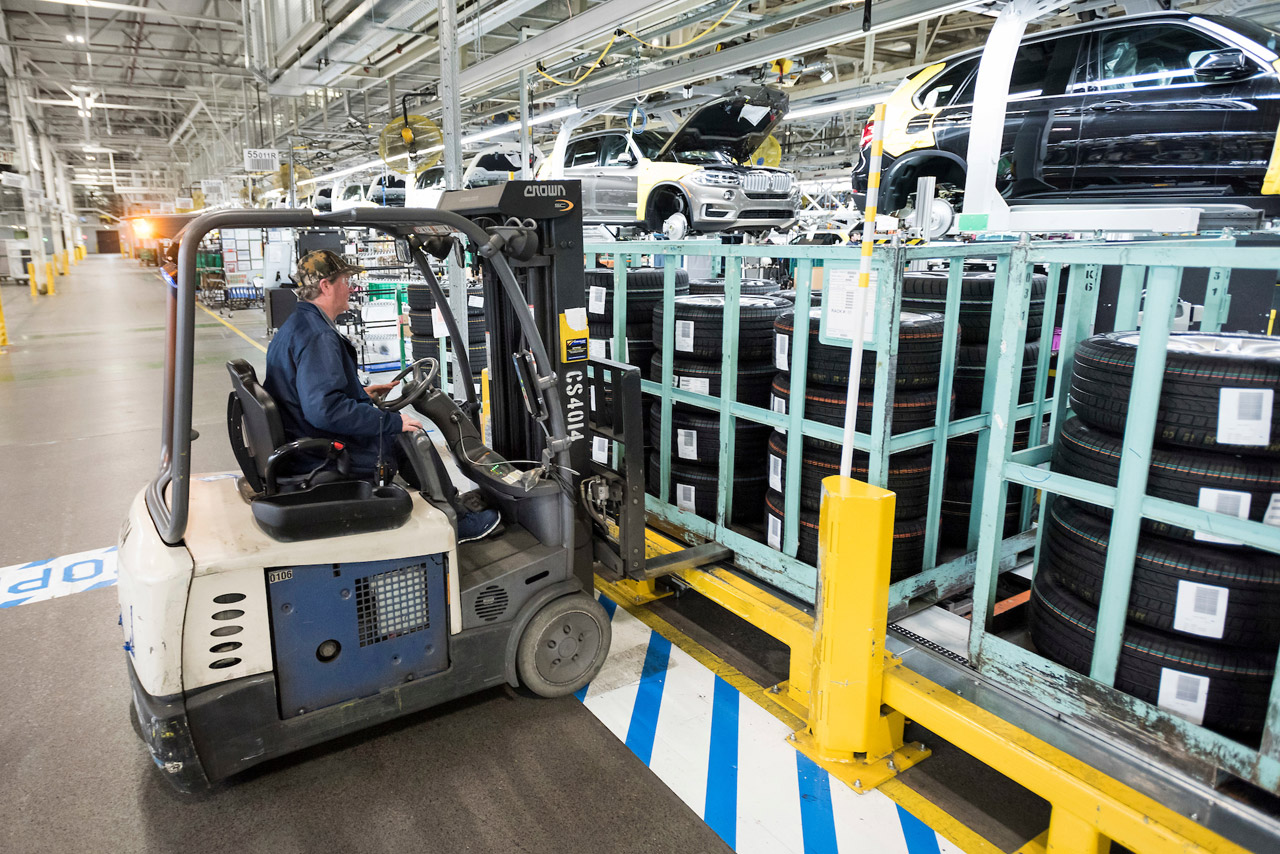 Forklift operator dropping off a rack of wheels in the production area. 