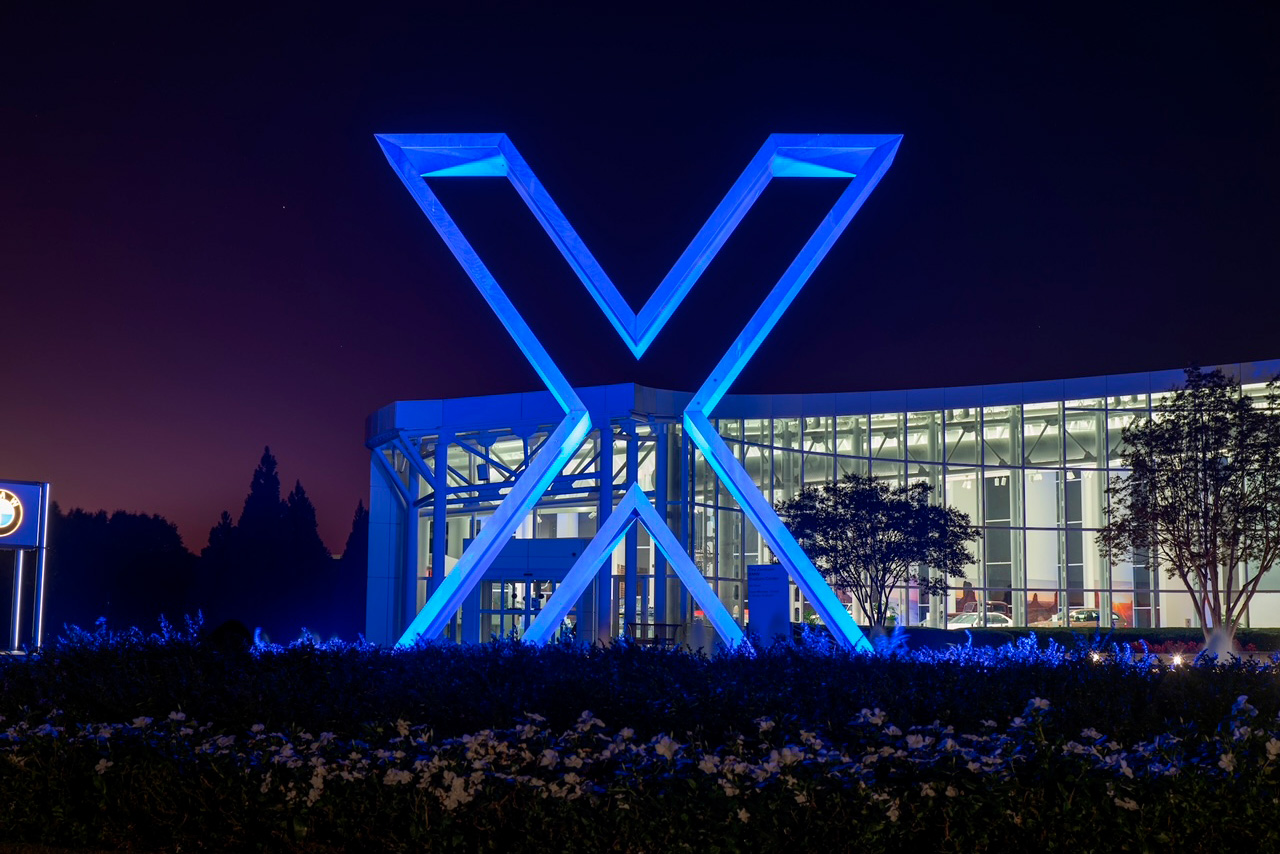 X logo sculpture in front of a building