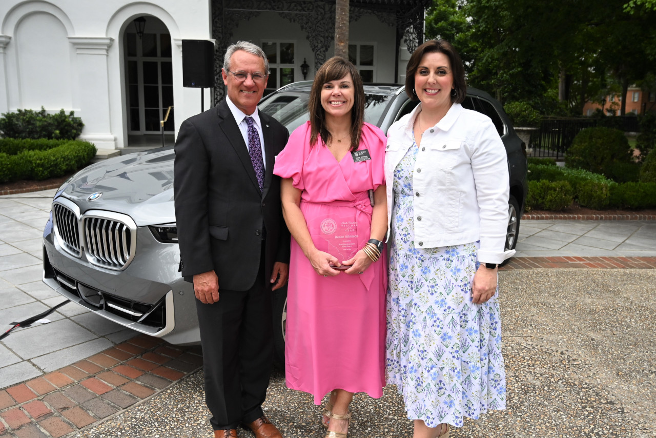 South Carolina's 2024 Teacher of the Year standing outside the governor's mansion in front of a BMW X5, flanked by BMW and Educational representatives. 