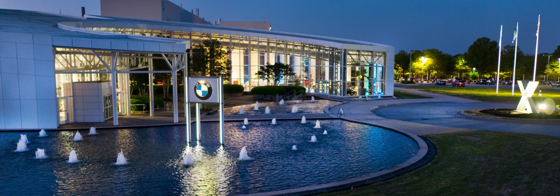 Zentrum Museum lit up at night with X display and fountain out front. 