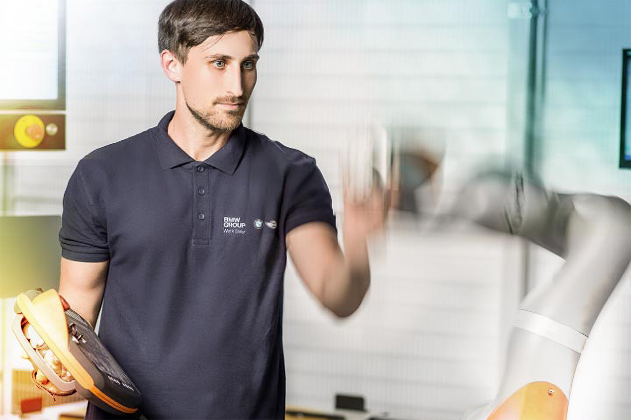 Mensch in der Produktion, der mit einem Roboter zusammenarbeitet.