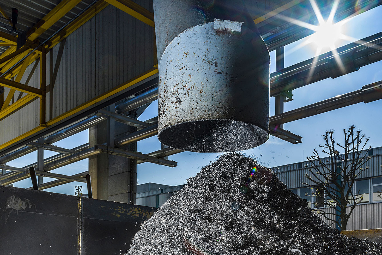 Späne die im Recyclingprozess durch ein Rohr auf einen großen Haufen fallen.