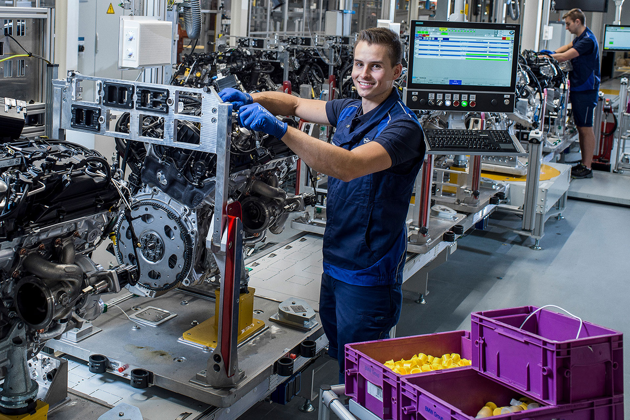 Arbeiter im Steyr Werk bei der Motorenmontage lächelt in die Kamera