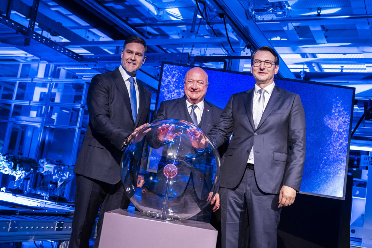 Three men in suits pose next to a large, shiny glass ball.