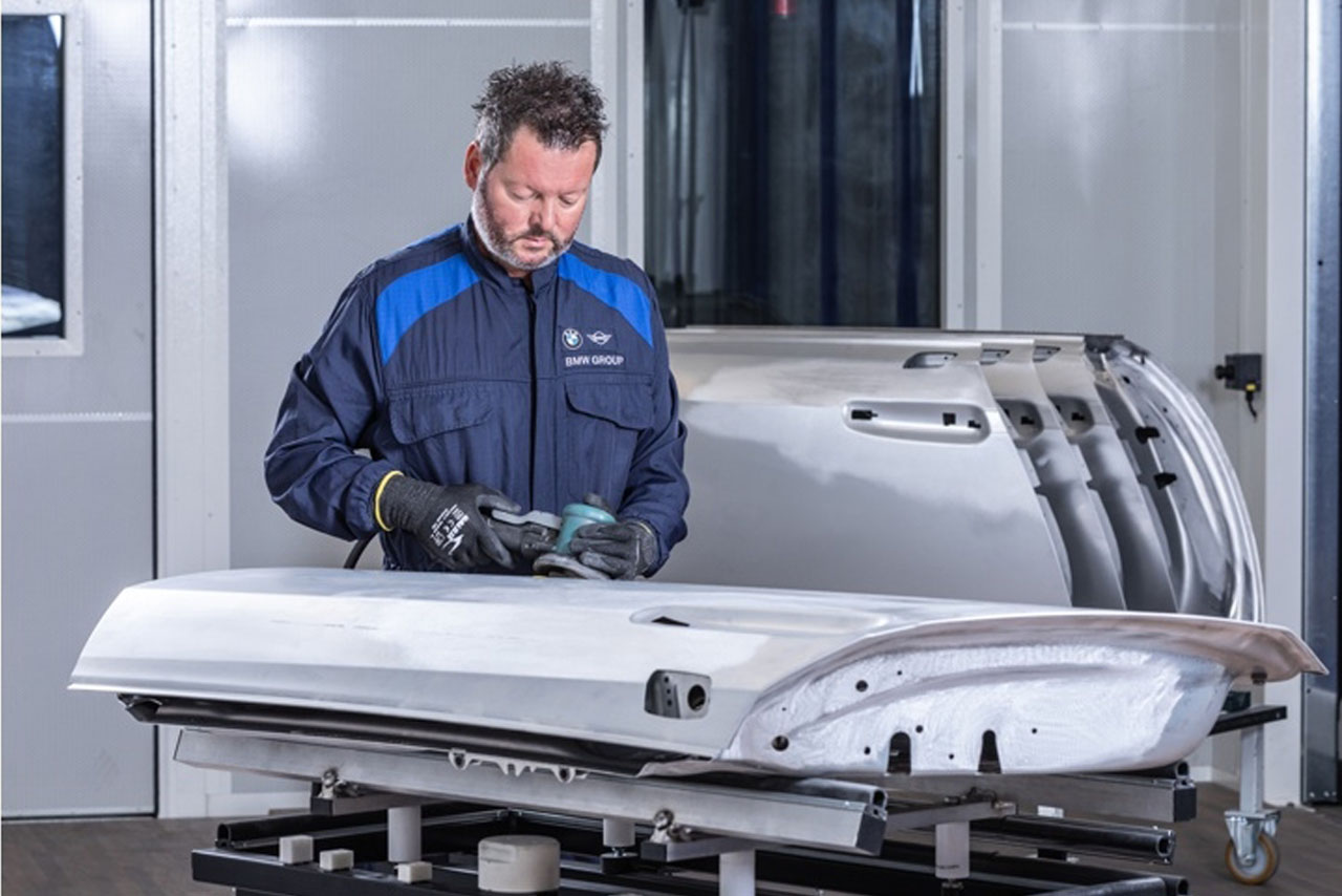 Ein Mann arbeitet mit einer Poliermaschine an einer weißen Fahrzeugtüre.