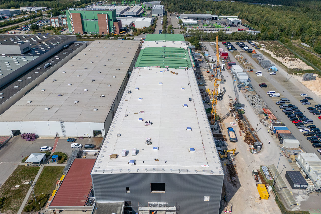 Aerial view of the BMW Wackendorf plant with a large roof surrounded by other industrial plants.