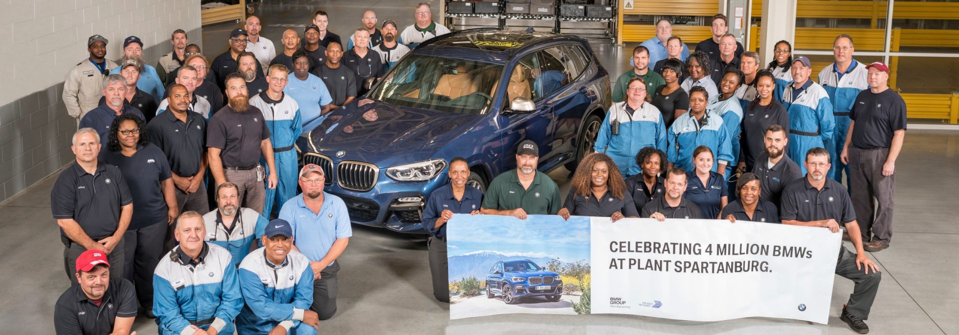 Associates celebrating four millionth BMW Assembled at Plant Spartanburg. They are gathered around the vehicle with a banner. 