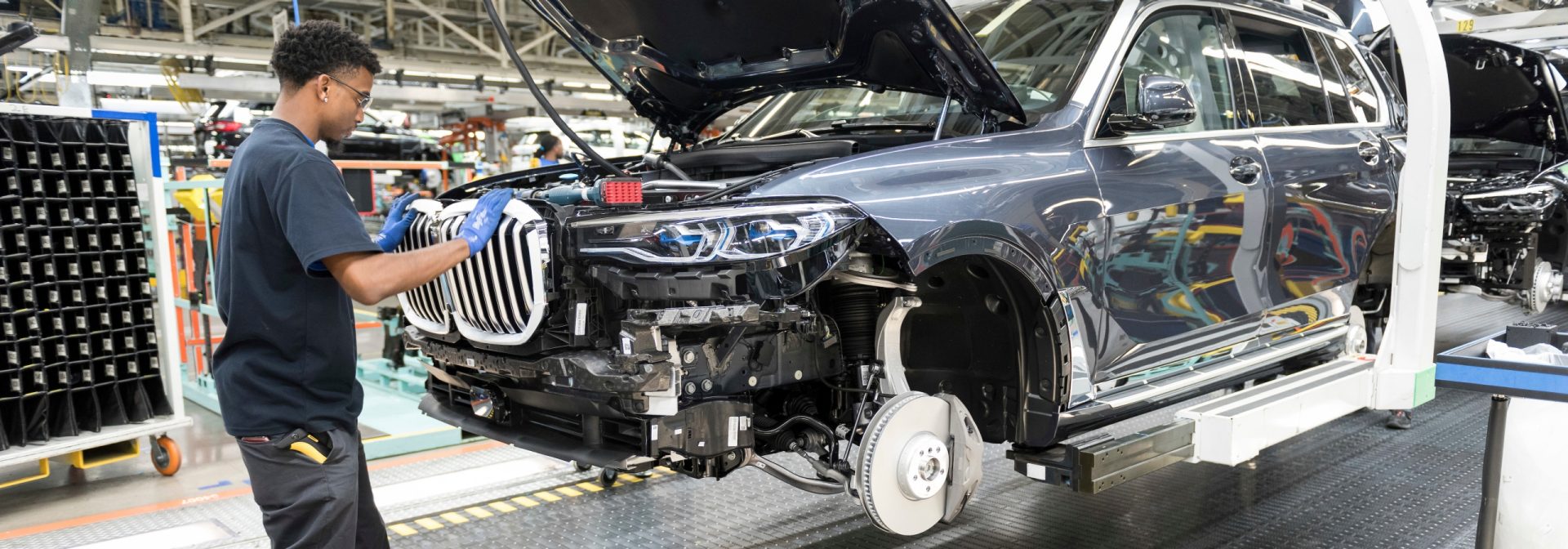 The first BMW X7 Sports Activity Vehicle on the assembly with an associate putting on the grille. 