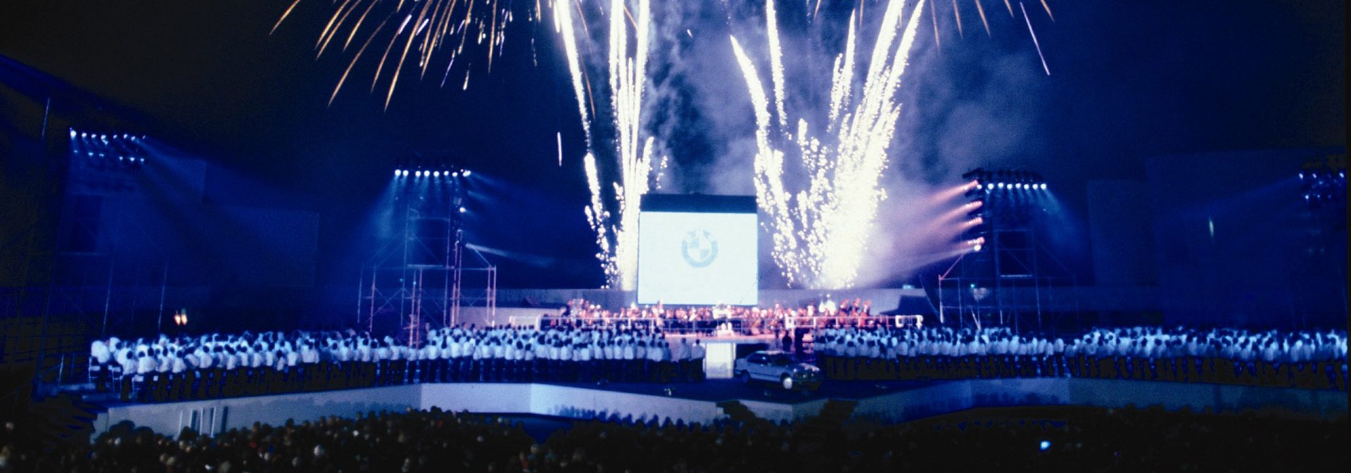 Opening ceremony event with fireworks and associates on stage with first car produced. 